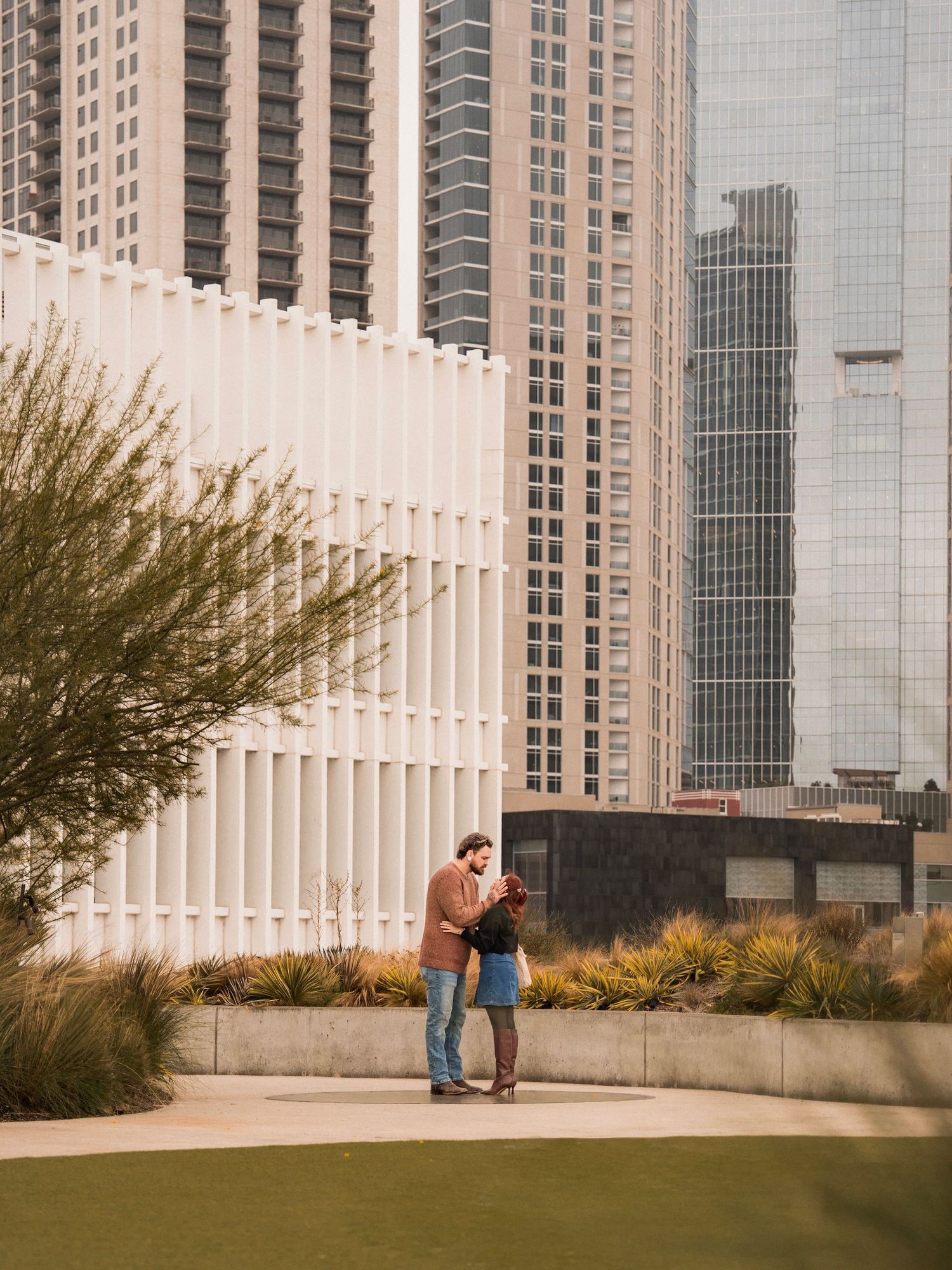 A romantic proposal scene unfolds in front of modern architecture with vertical white columns.