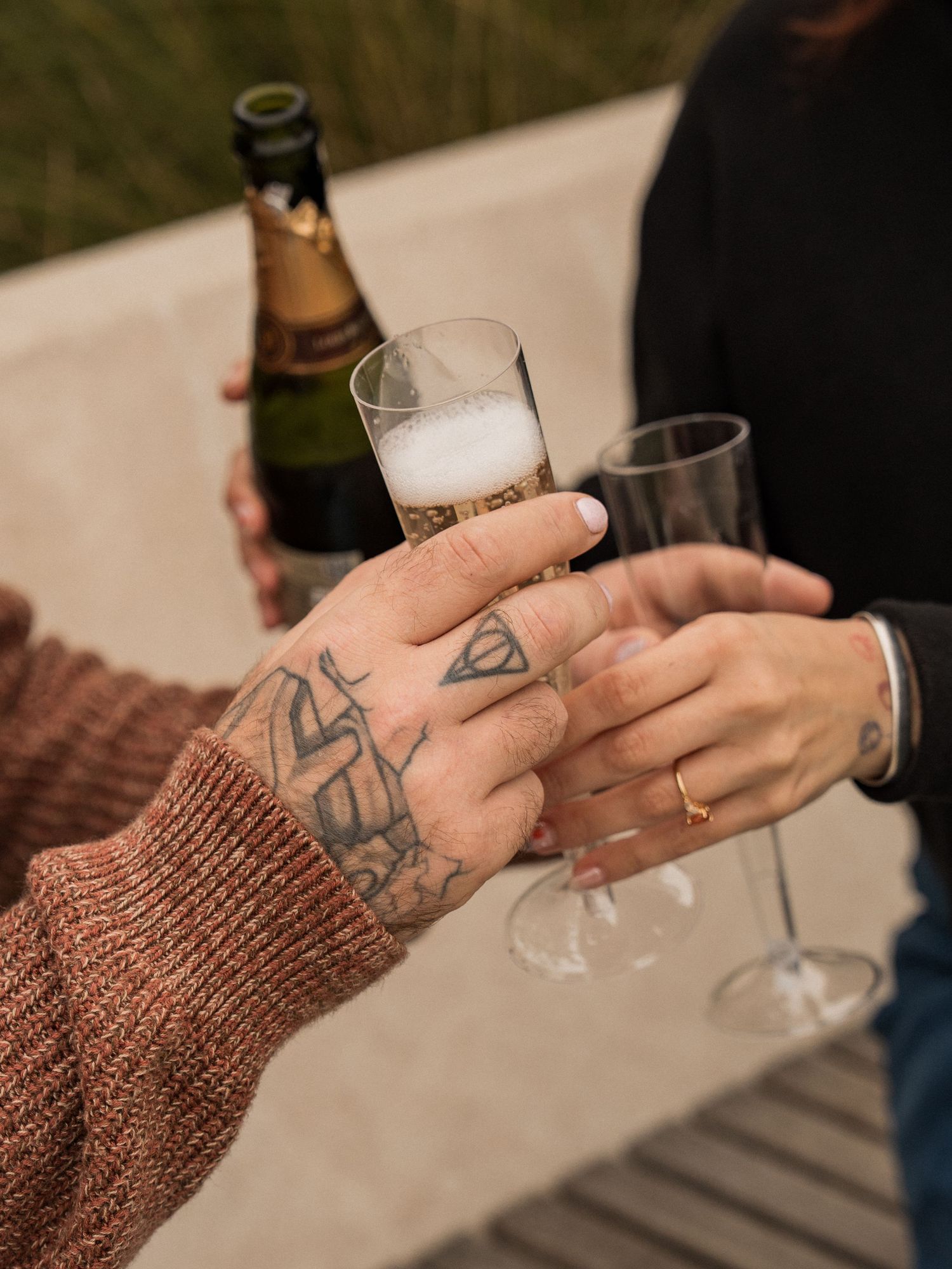Close-up shot of hands holding wine glasses in warm evening light.