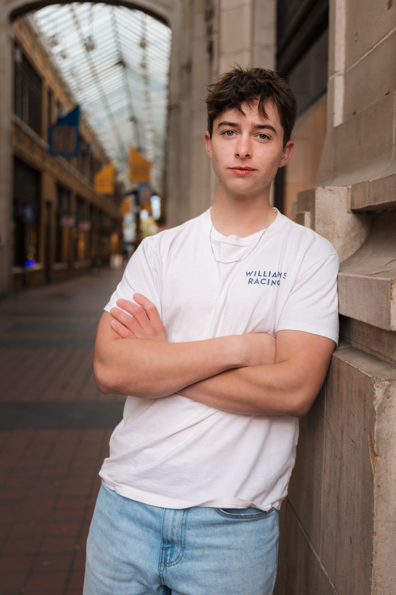 Senior boy learning against a wall in Nickels Arcade in downtown Ann Arbor. He is posing for a senior photo.