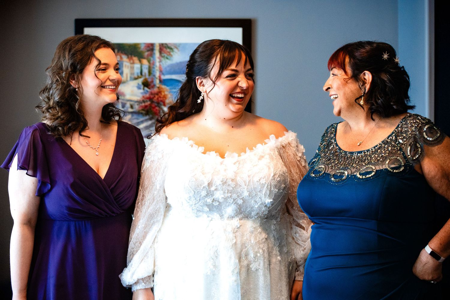 A group of people laughing and celebrating at a wedding event in navy blue and white attire.