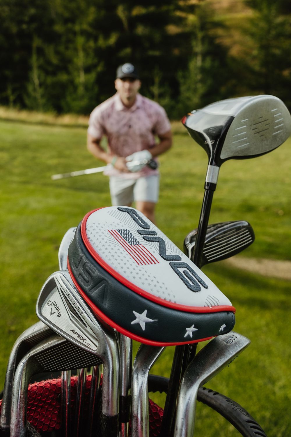Close-up of patriotic golf club heads with American flag designs and star details on a sunny golf course.