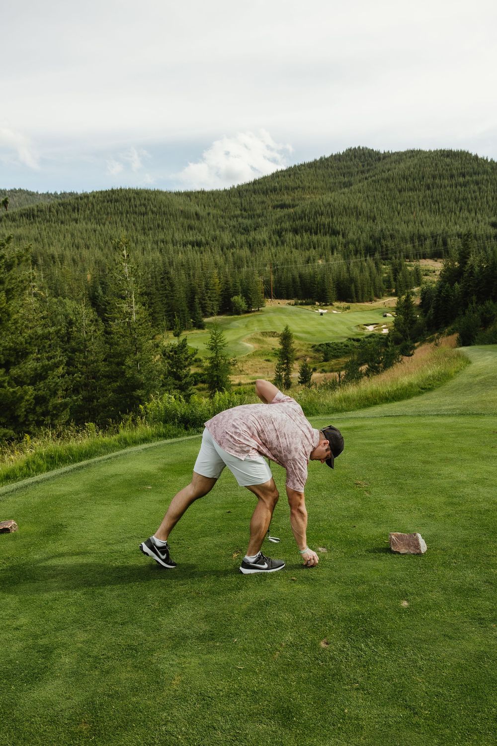 Sequence showing a golfer setting up and taking a shot on a mountain golf course.