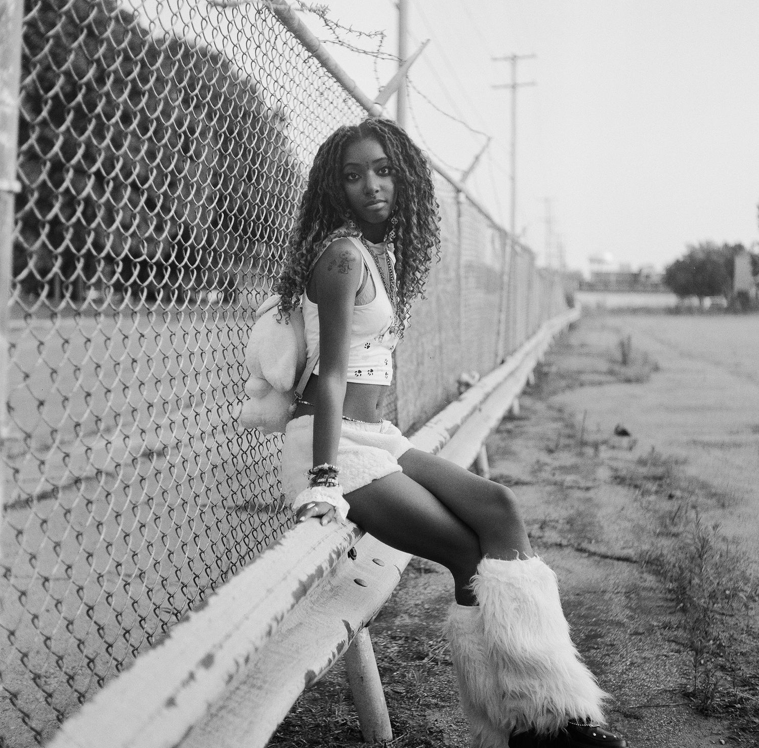A black and white photo series showing a person in dance-like poses against a chain link fence outdoors.