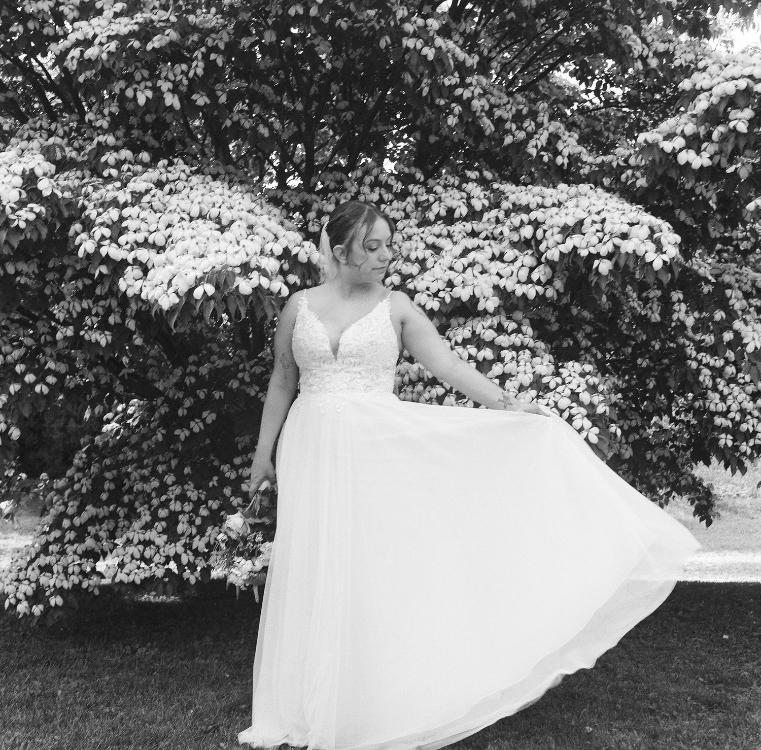 A flowing white dress twirls gracefully in motion against a natural outdoor backdrop with trees and foliage.
