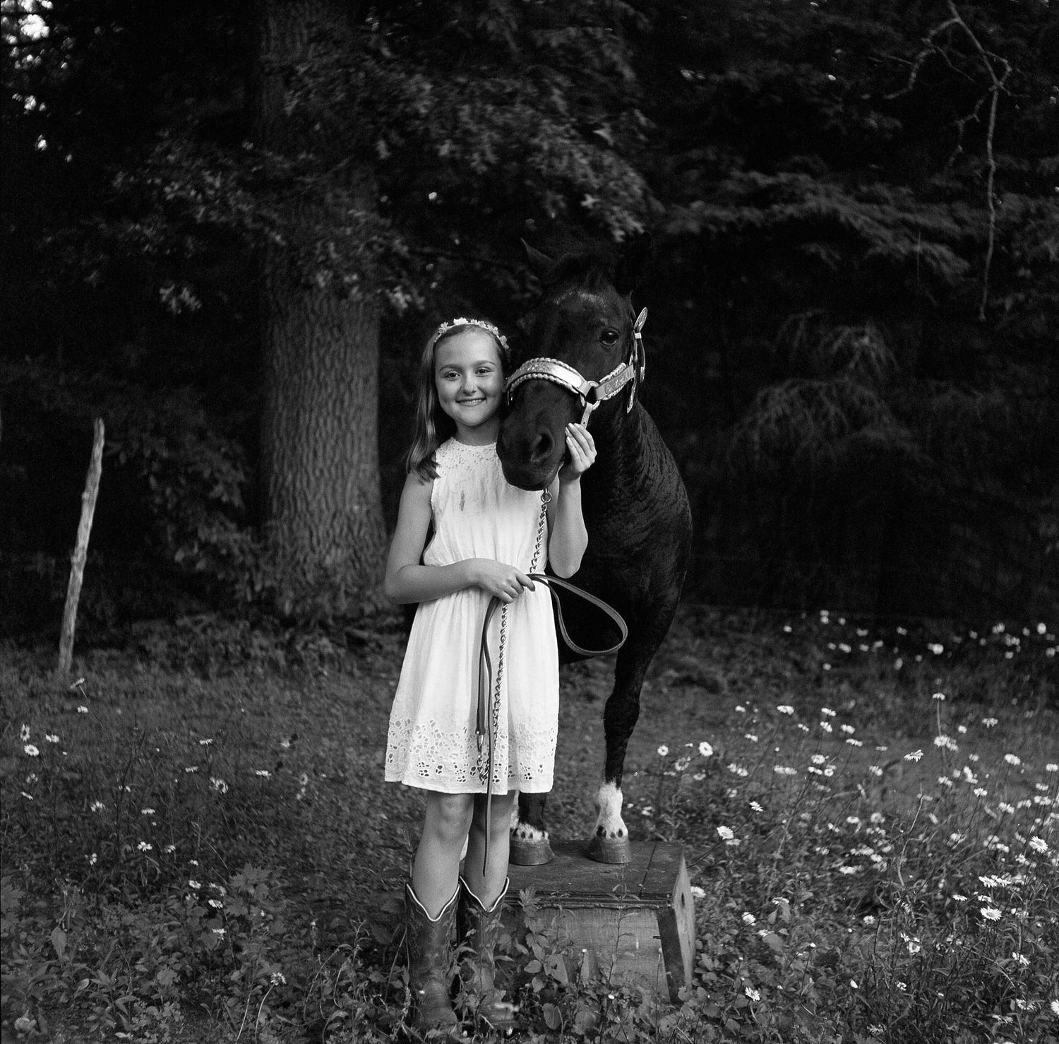 A black and white photo sequence shows a person in a dress walking through a wooded area with scattered flowers.