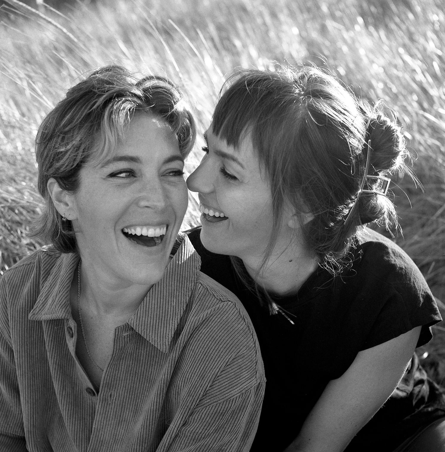 Black and white sequence showing two people sharing joyful moments and laughter in a natural outdoor setting.