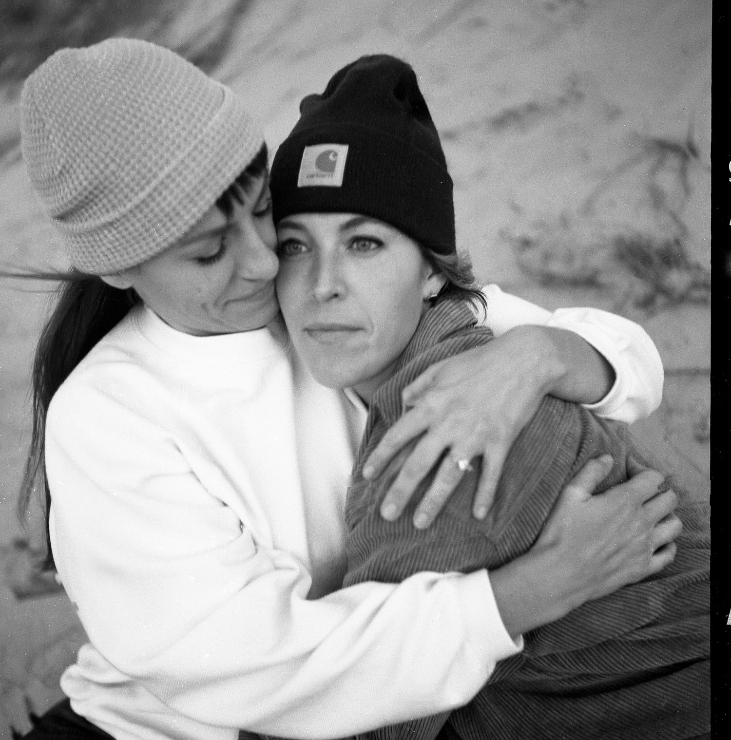 A black and white series of intimate photos showing two people in close embrace wearing winter hats.