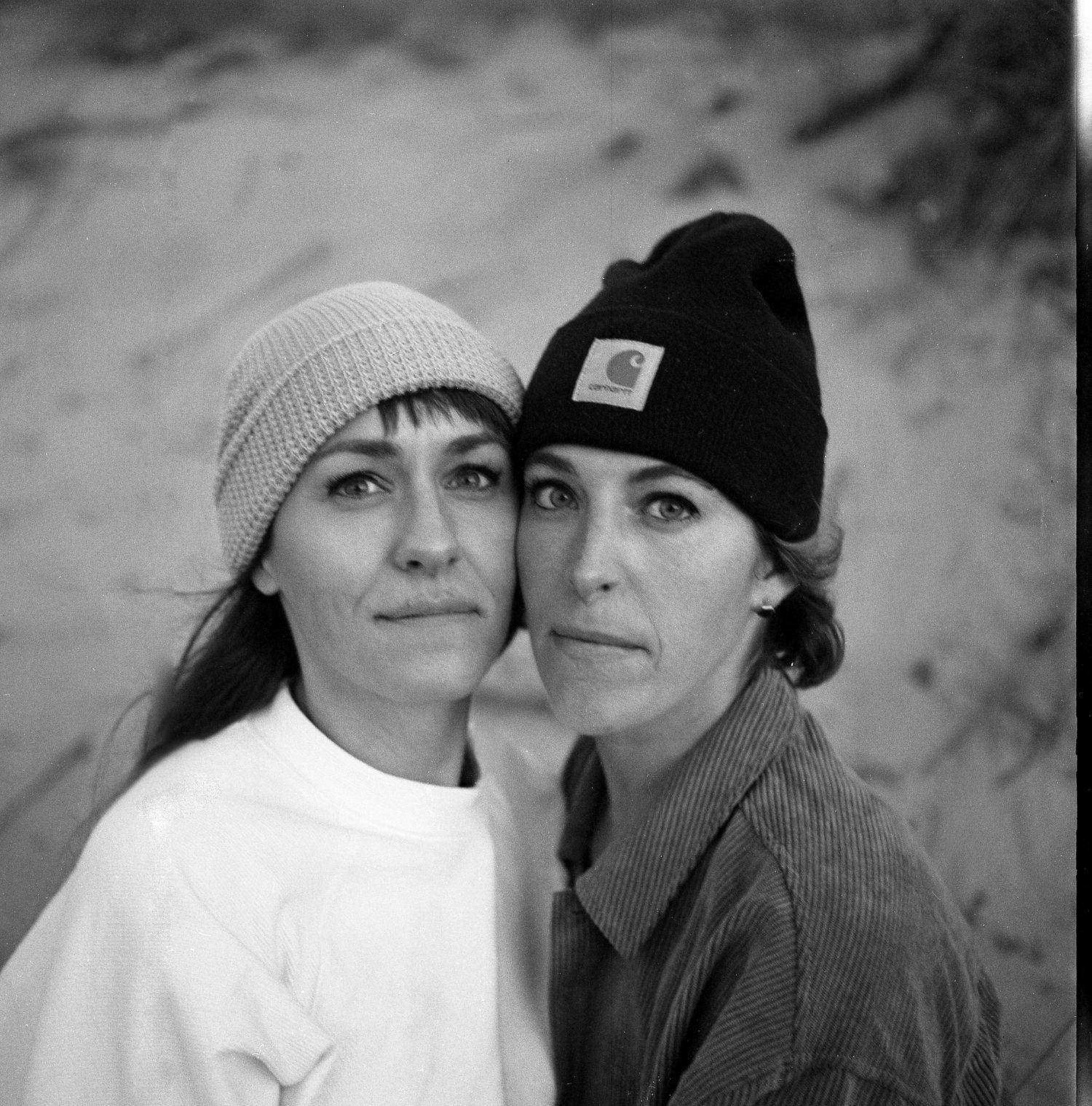 Black and white artistic portrait series showing couple in winter hats sharing intimate moments together.