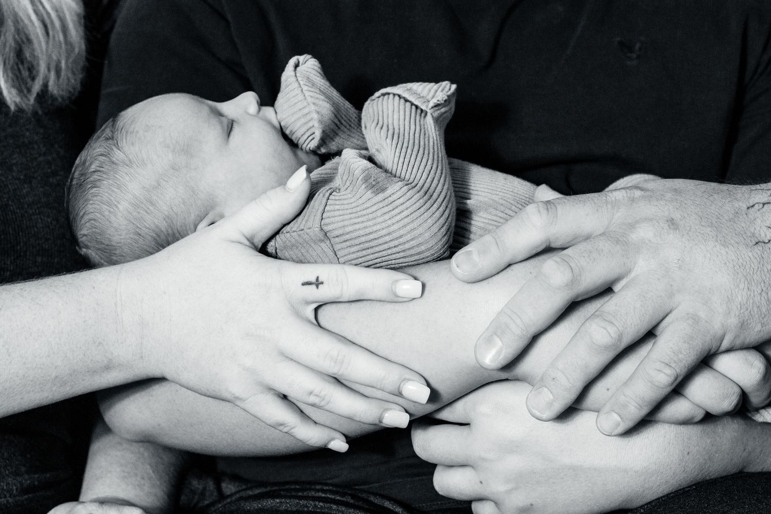 A black and white photograph shows hands gently touching and intertwining in an intimate gesture.
