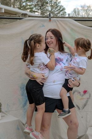 Children create colorful artwork by painting on a large canvas sheet outdoors during a fun art activity.
