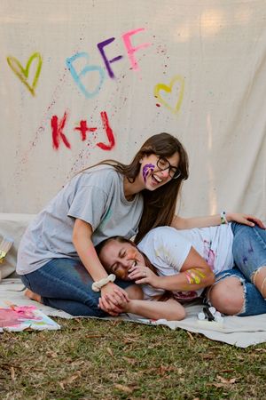 Playful moments captured on the ground against a white backdrop with colorful painted letters and designs.