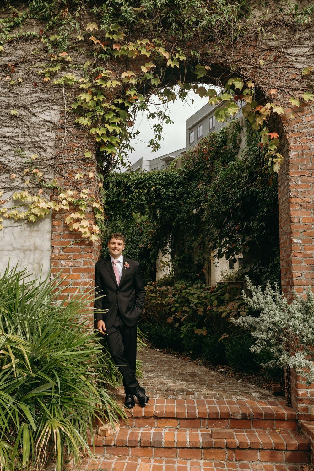 Groom leaning on ivory wall at Summerour Studio in Atlanta, Georgia