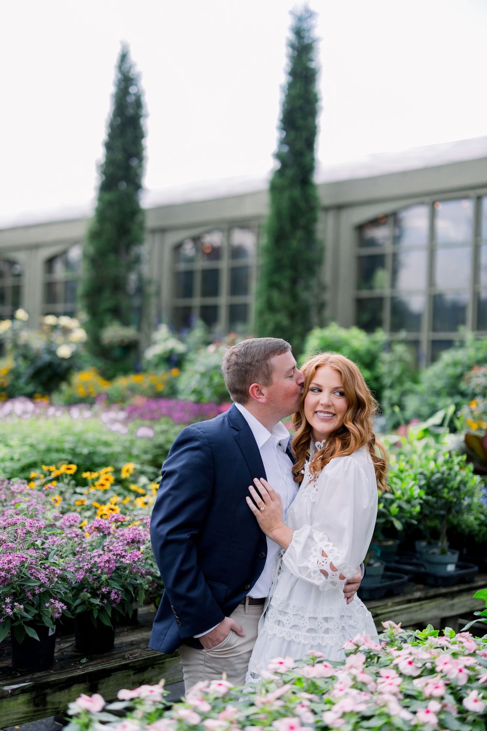 A couple shares tender moments among colorful flower gardens and cypress trees on a romantic afternoon.