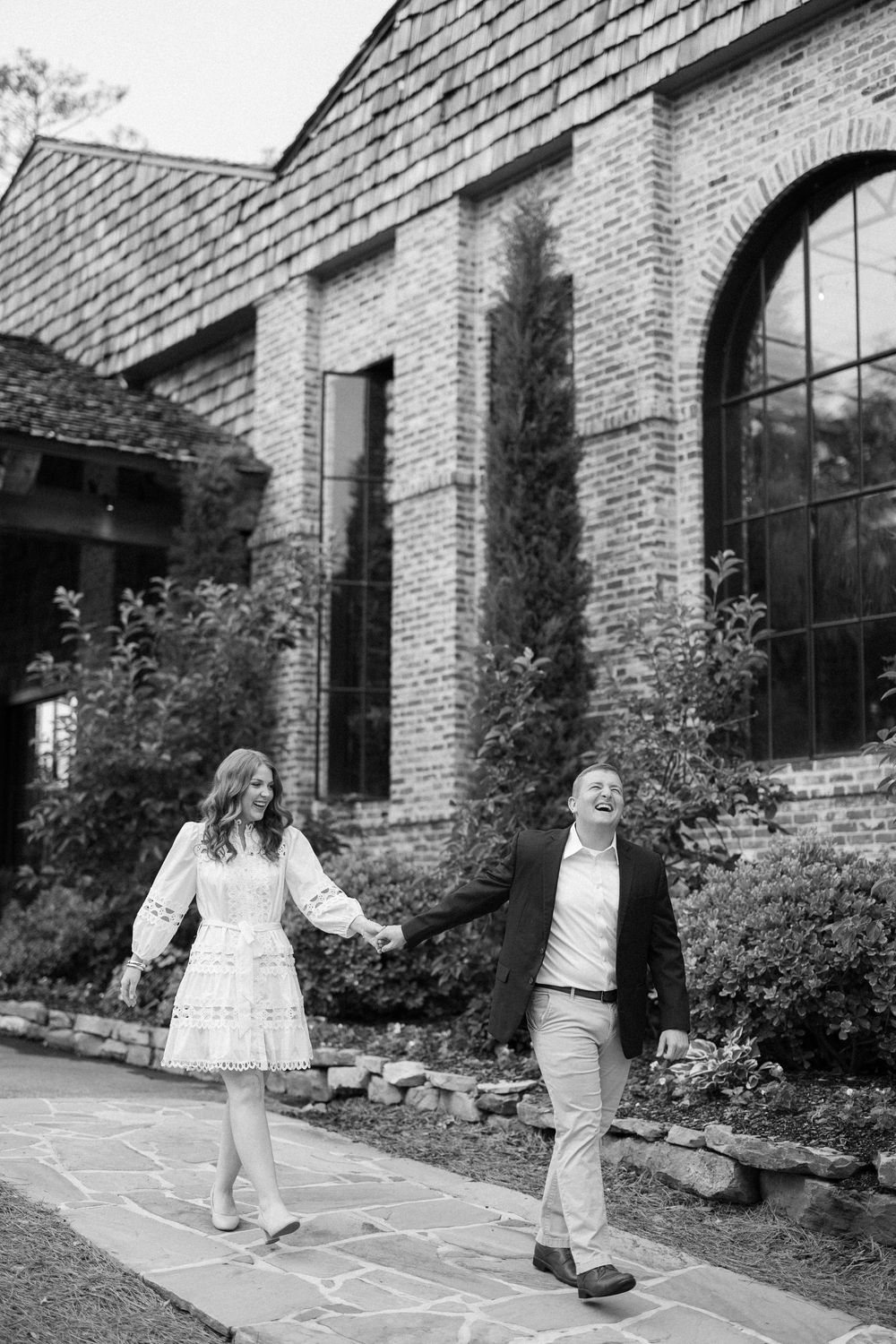 Children playing hopscotch on a sidewalk outside a brick building with large windows.