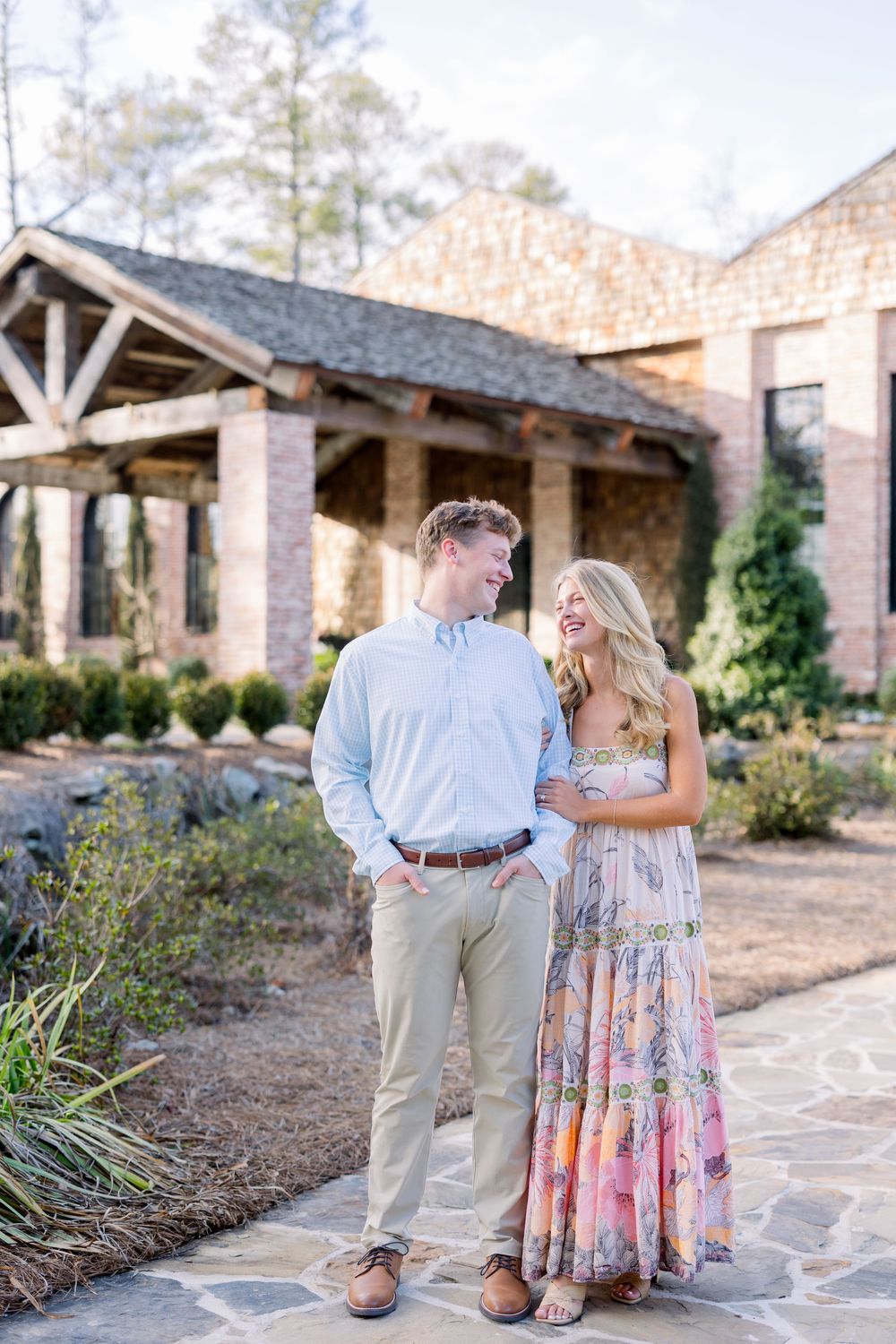 A romantic moment unfolds on a flagstone path with stone buildings and greenery creating a scenic backdrop.