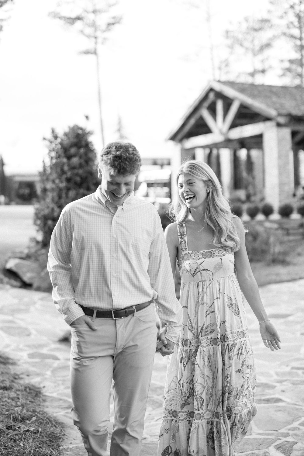 A couple shares a joyful moment walking together outdoors in coordinated white and beige outfits.