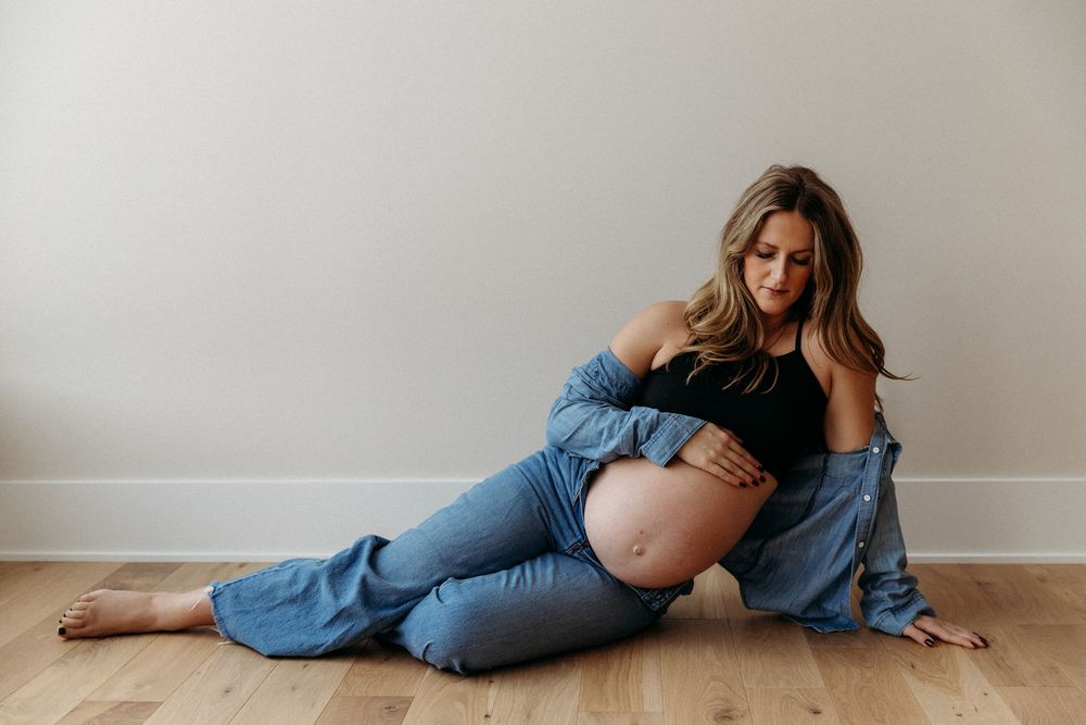 Relaxed floor poses during maternity photoshoot with denim styling.