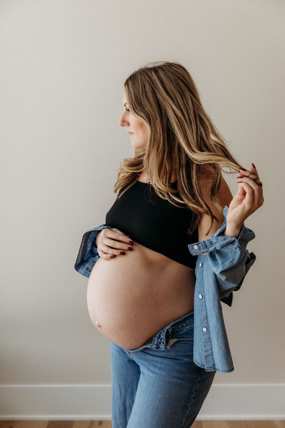 Artistic maternity photos showing pregnancy belly with casual denim outfit.