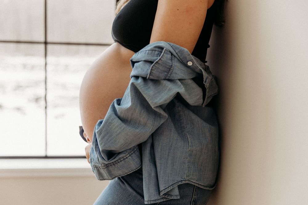 Minimalist maternity photo series with denim and black outfit.