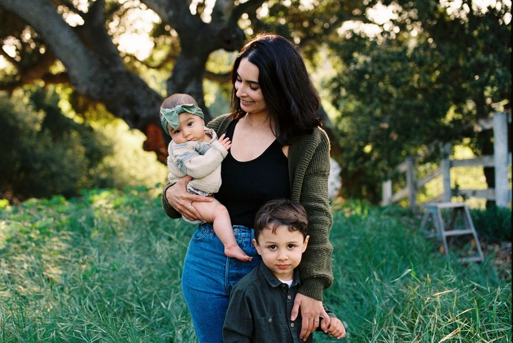 A family enjoys quality time together in a sun-dappled outdoor setting during golden hour.