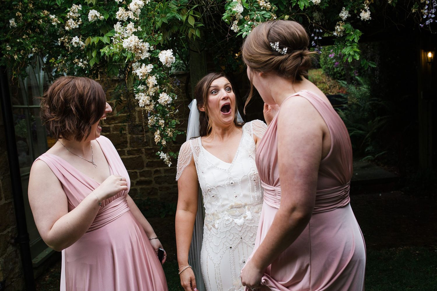 Bride reacting with excitement alongside bridesmaids during wedding day preparations