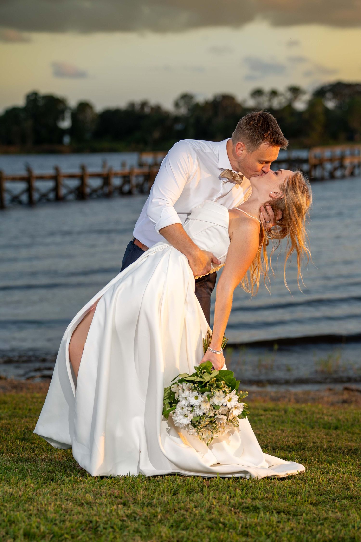 Romantic sunset wedding photos taken on a beach with wooden pier and ocean views in the background.