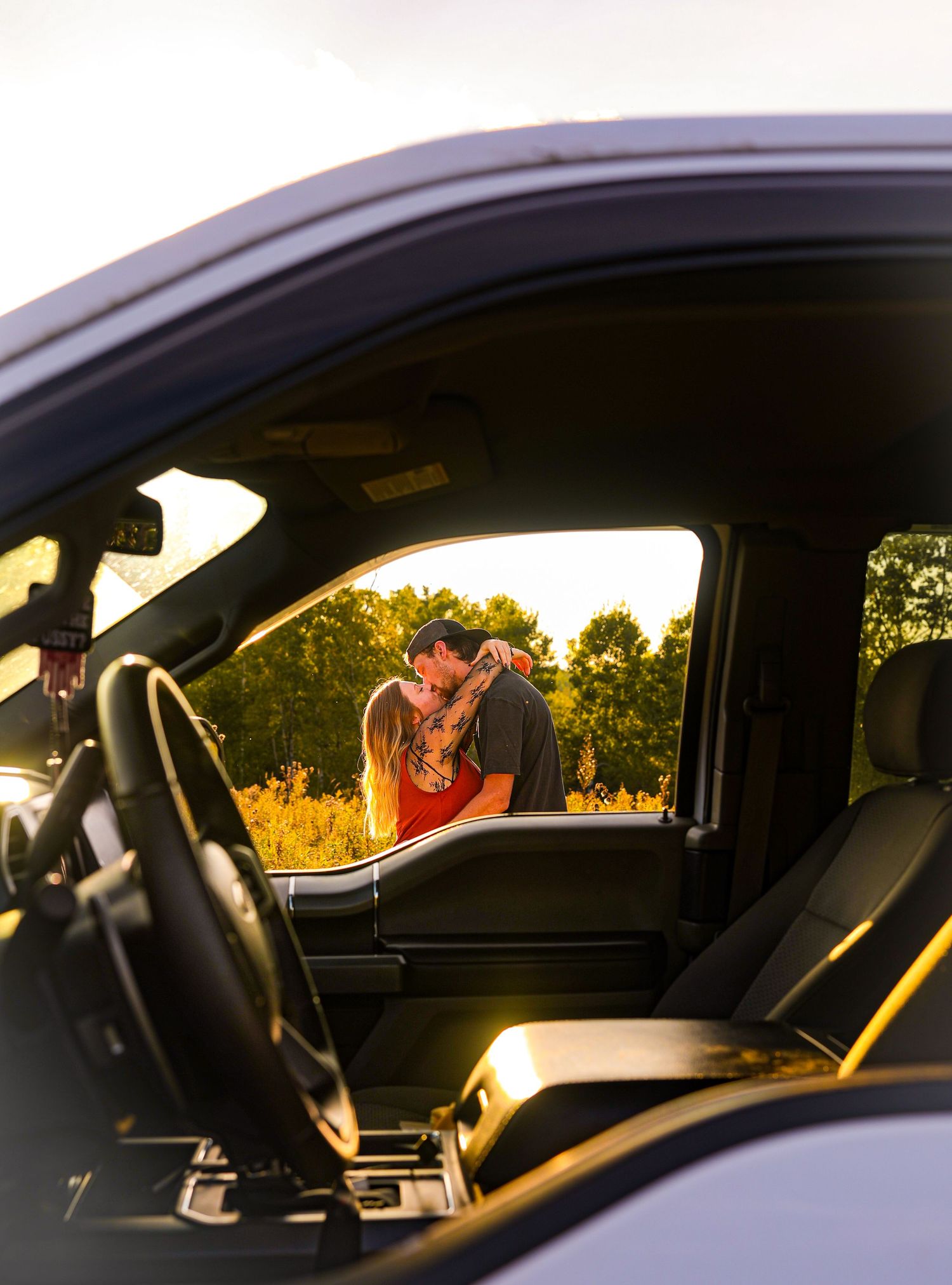 Couple truck inspiration pose of couple kissing on the other side of the truck.