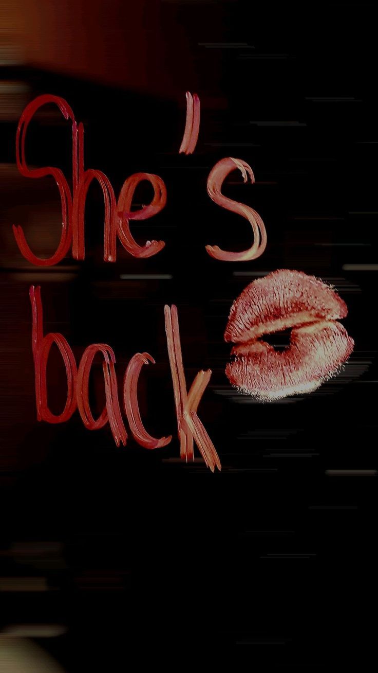 Red lipstick kiss marks and text written on a dark black surface create a mysterious and artistic composition.
