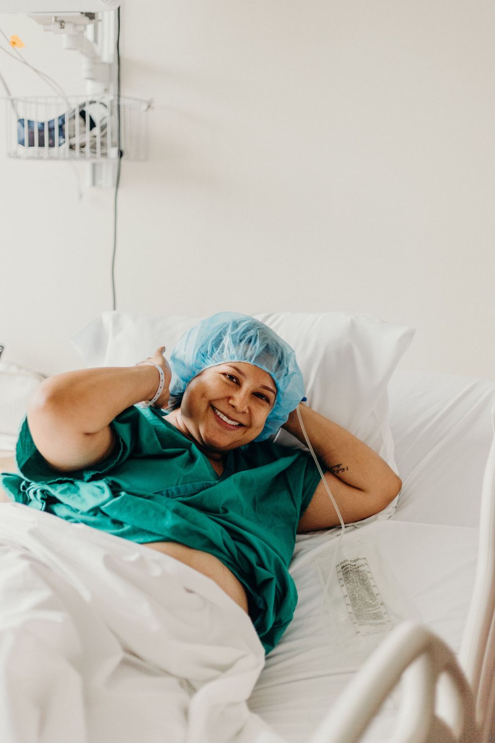 Patient in hospital gown resting comfortably on a medical bed with a cheerful expression.