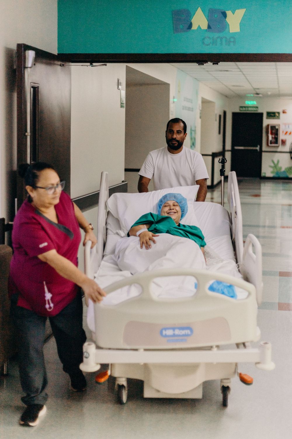 Medical staff transporting patient in hospital bed down a bright corridor.