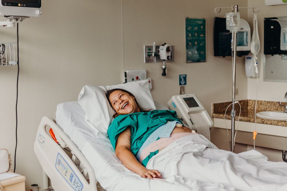 Patient resting in hospital bed with medical equipment and monitors visible in the background.