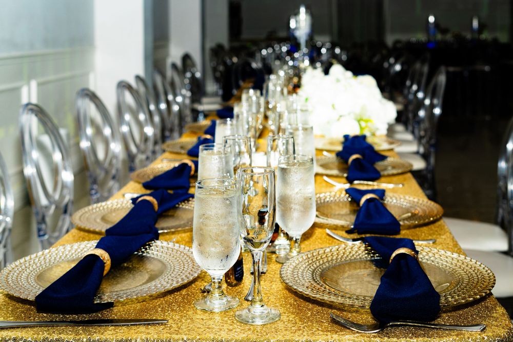 Elegant table settings with navy blue napkins and gold charger plates at a formal event.