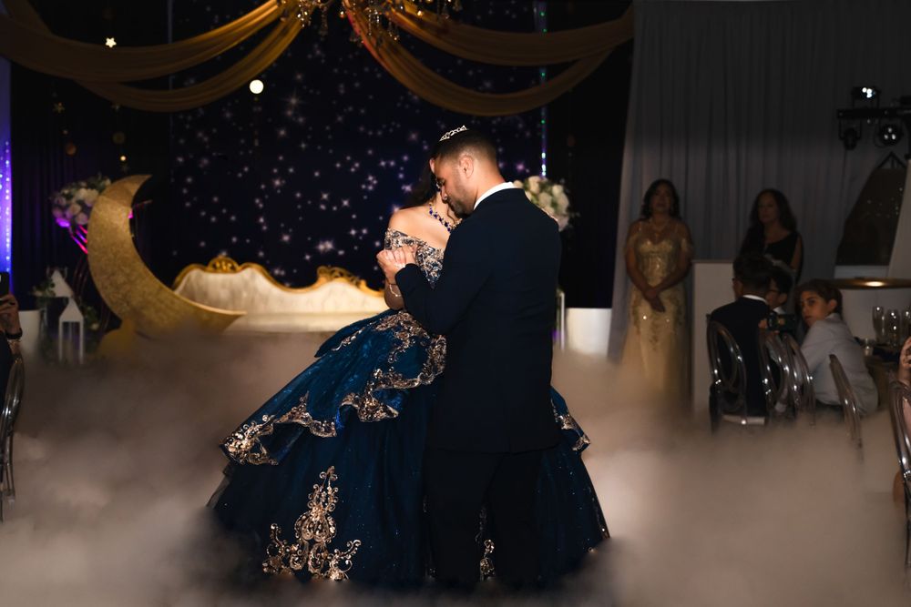 Couple dancing on a misty dance floor with decorative moon backdrop.