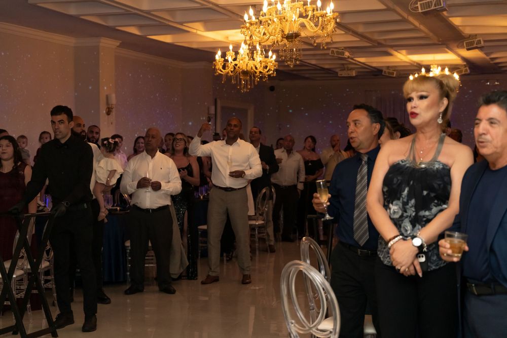 Formal event space with golden chandeliers and guests mingling in evening attire.