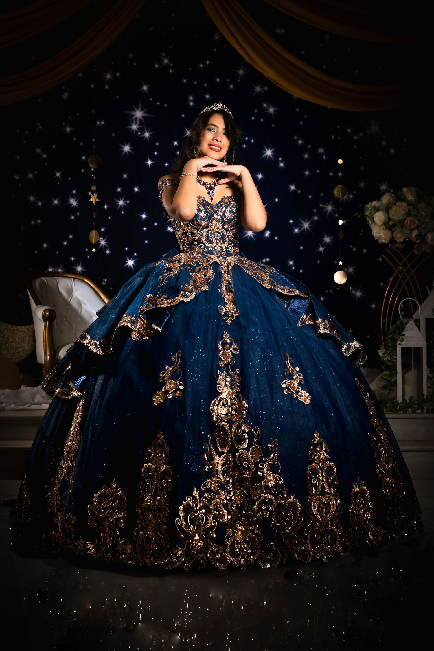 Stunning navy blue ball gown with gold embellishments photographed against starry backdrop.