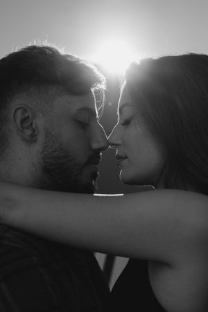 Black and white close-up portrait of couple in intimate pose with backlight.