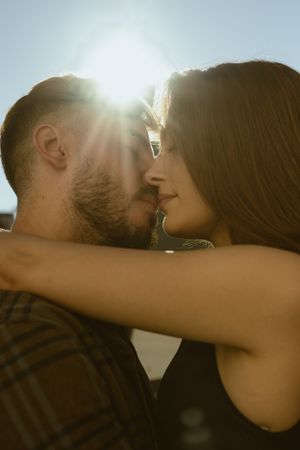Sunlit close-up of couple in tender moment wearing casual attire.
