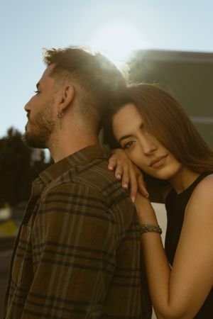 Golden hour portrait of couple with sun flare and urban background.