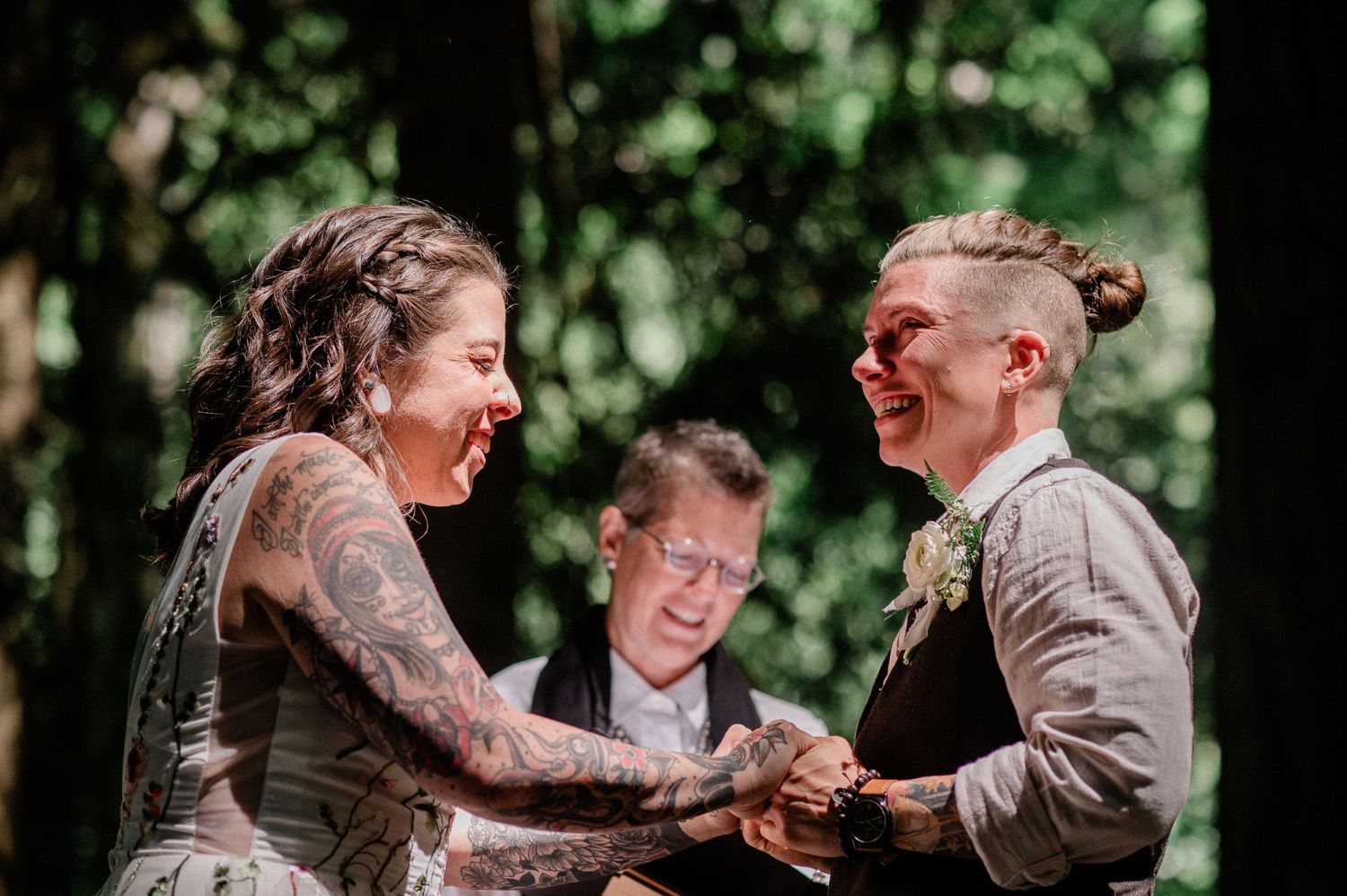 two brides and officiant all laugh during ceremony