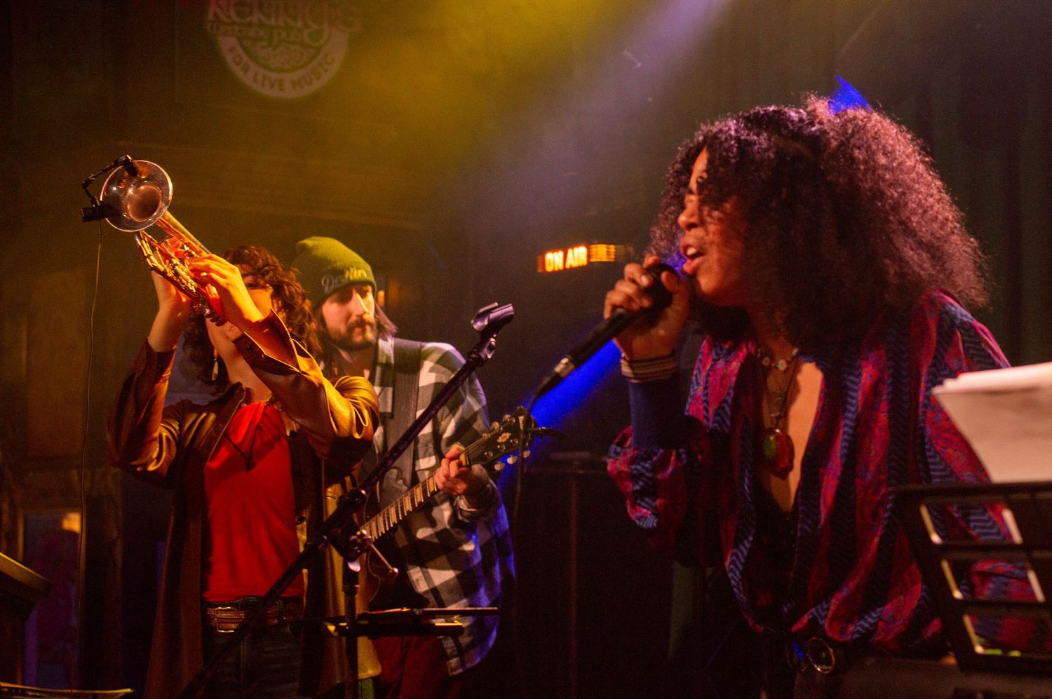 Musicians performing energetically on stage with colorful concert lighting.