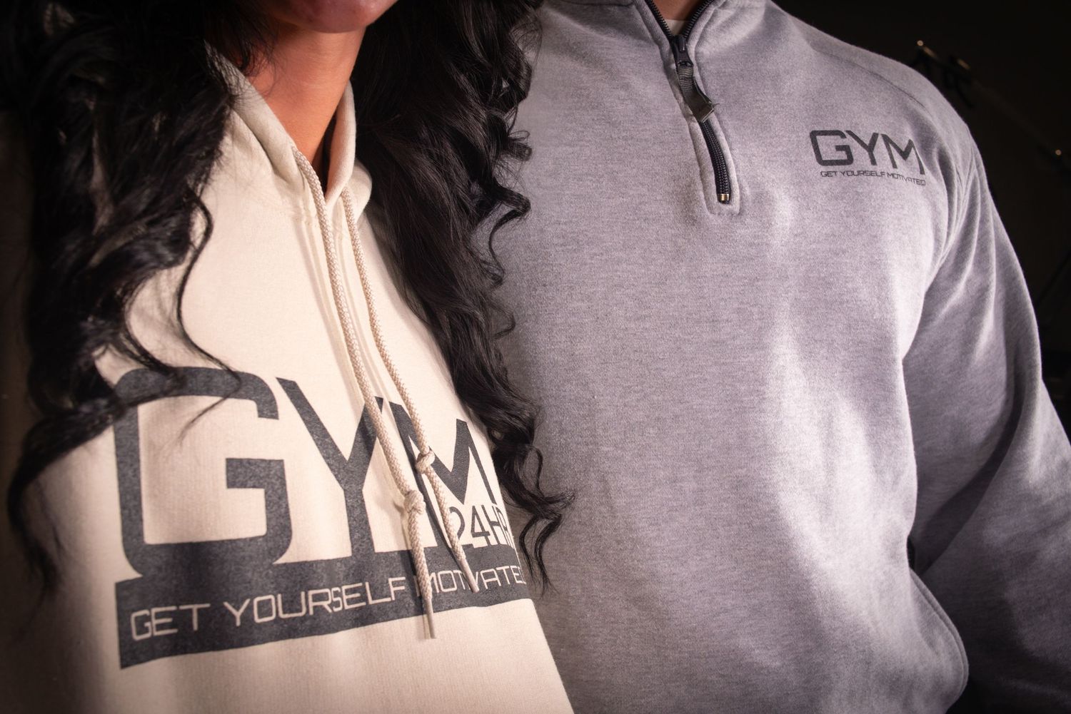Two people wearing matching GYM motivational sweatshirts in grey and white.