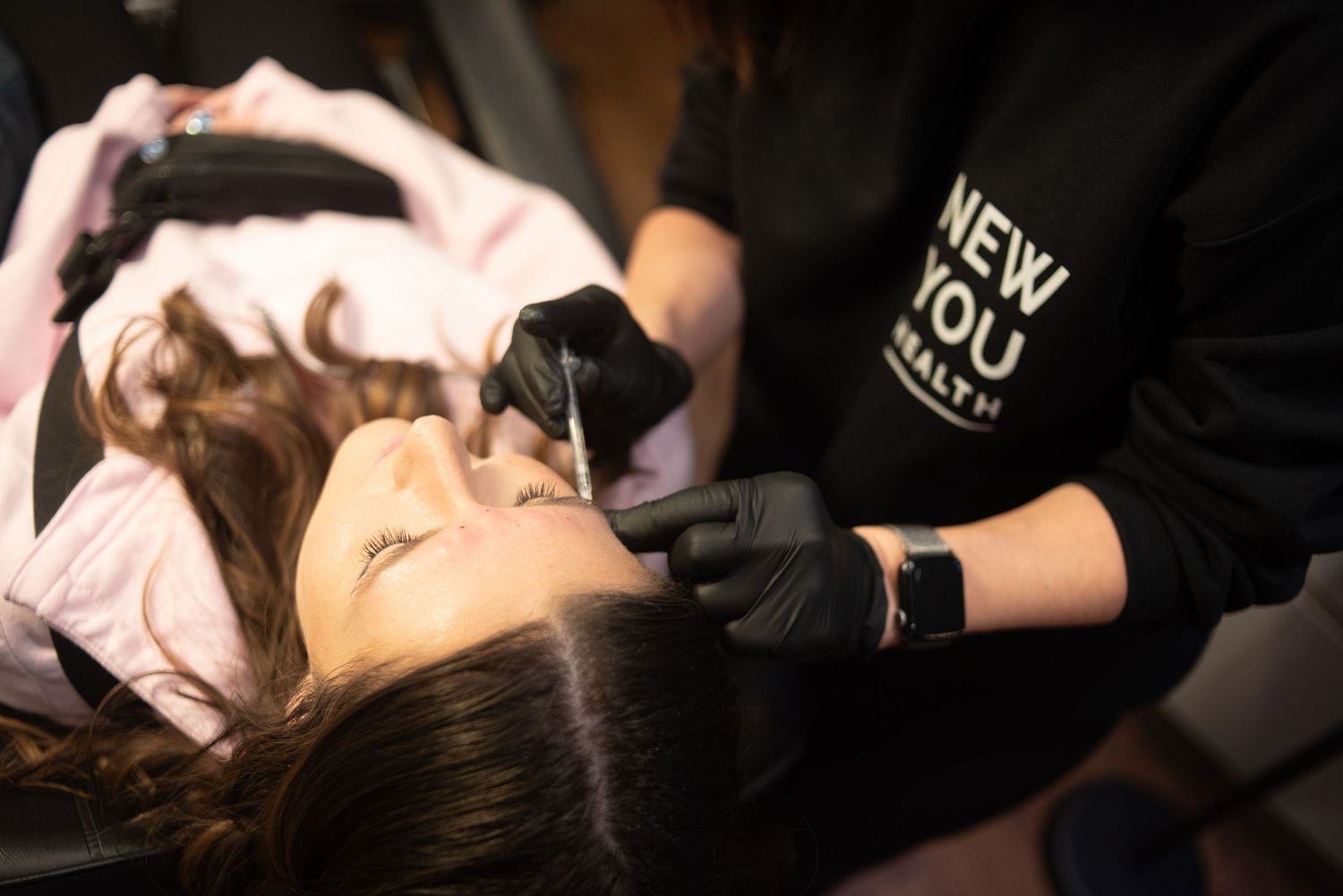Close-up of tattoo artist at work wearing black gloves and hoodie.