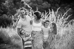 Black and white family group photo taken in tall grass, capturing a candid moment together.
