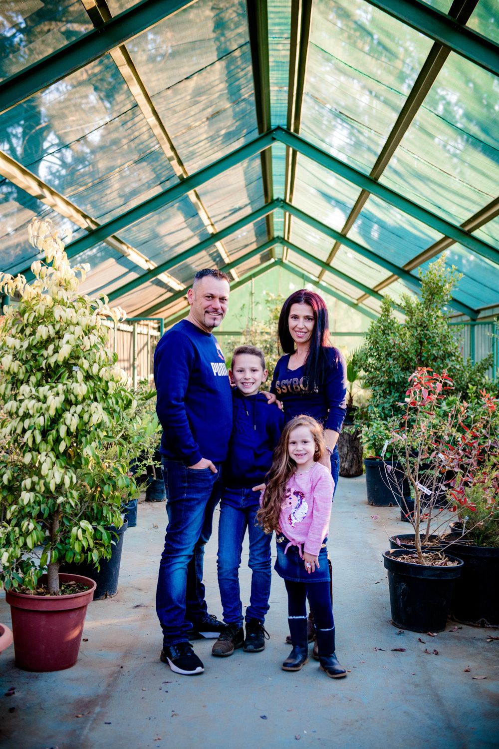 Family of four standing together inside a scenic greenhouse venue.