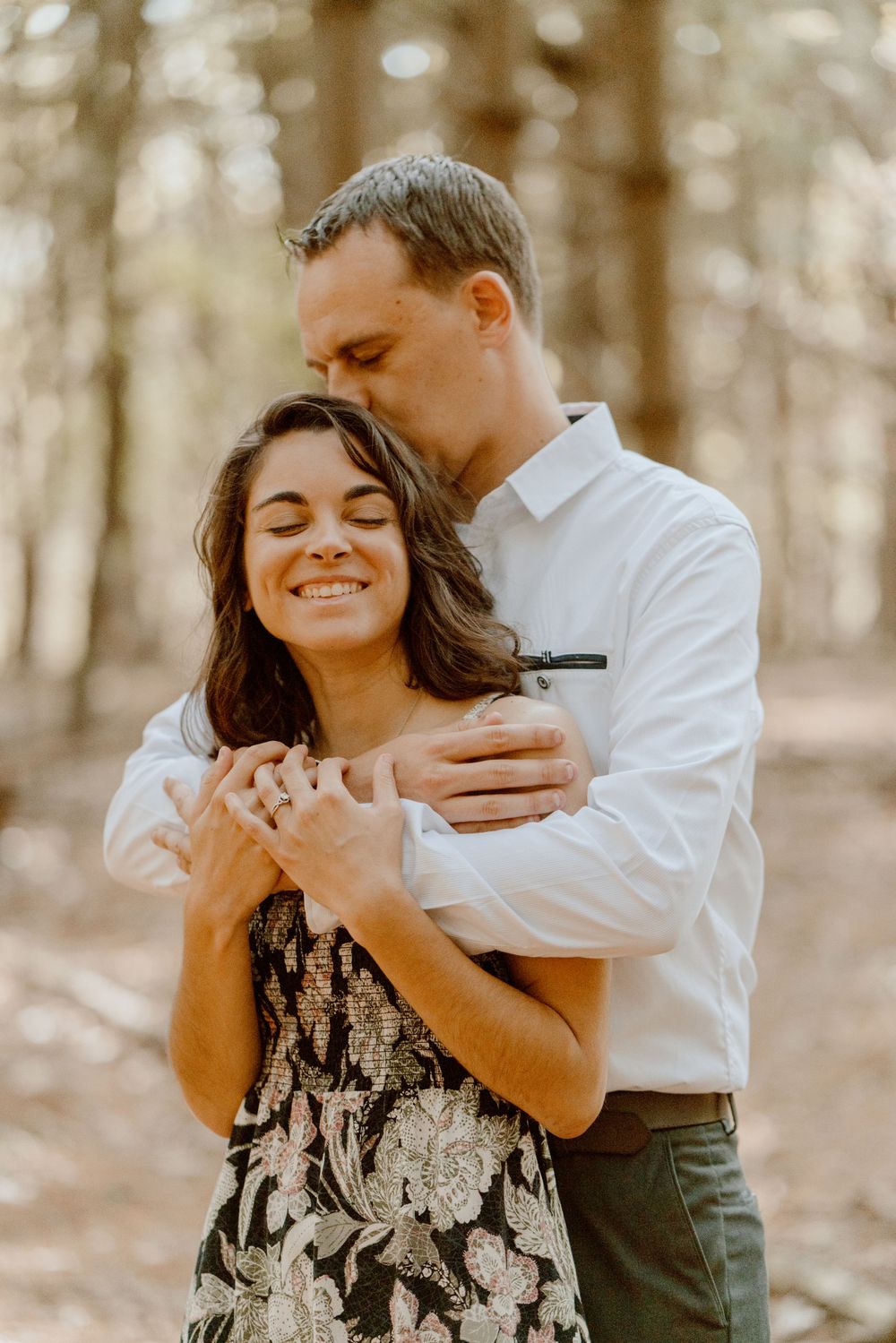 A couple shares joyful laughter during an intimate forest photoshoot.