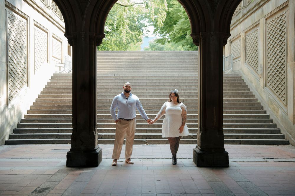 Newlyweds holding hands under Bethesda Terrace arches in Central Park on their wedding day.