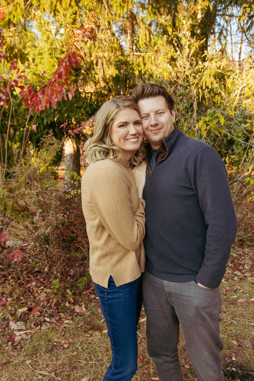 Casual outdoor autumn portrait of a couple embracing among fall foliage.