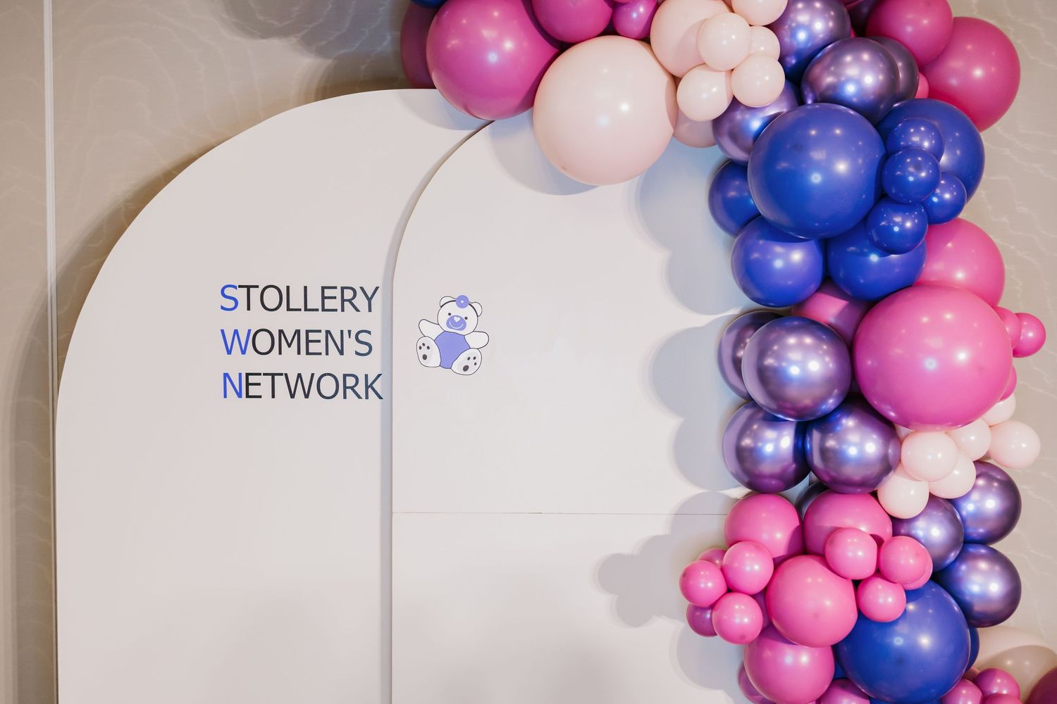 Pink and purple balloon arch decoration with Stollery Women's Network signage.
