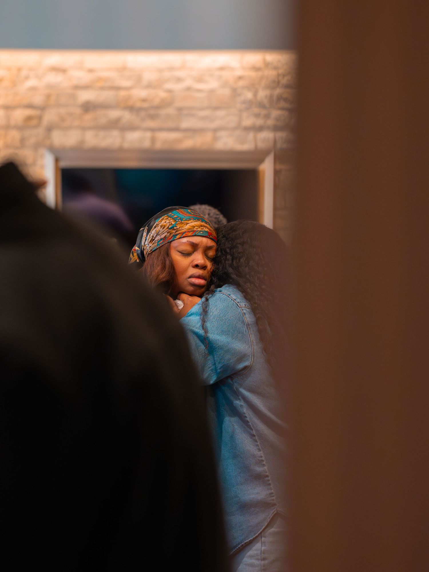 A person with long dark hair worshiping in deep prayer with eyes closed and arms raised.