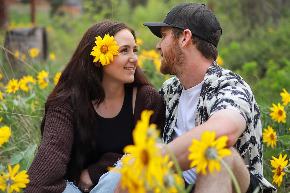 A couple sharing a tender moment surrounded by bright yellow wildflowers in a garden setting.